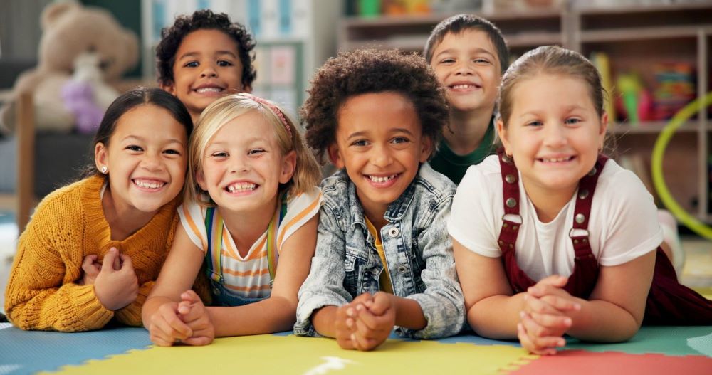 Smiling children leaning on a classroom table
